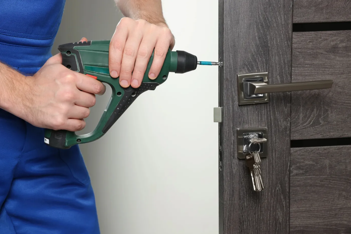 Serrurier fixant une serrure de sûreté sur une porte d'appartement à Levallois-Perret